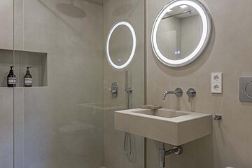 A bathroom with two round mirrors and a sink