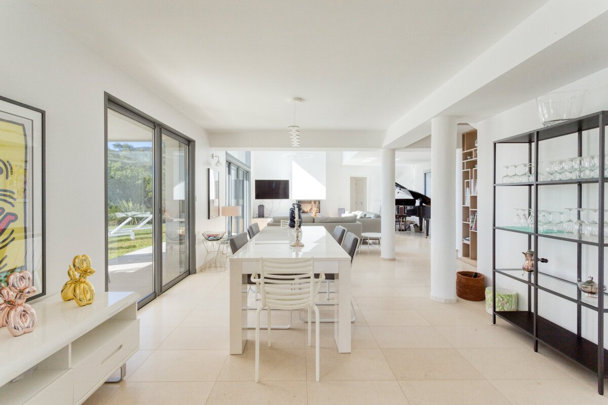 A dining room with a long white table and chairs