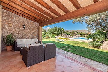A patio with a couch and chairs under a wooden roof