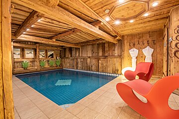 A wooden chalet with a large swimming pool