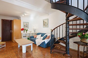 A living room with a spiral staircase leading up to the second floor