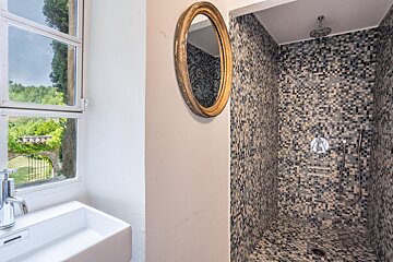 A bathroom with a walk in shower and a sink