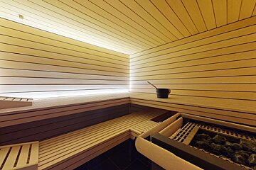 A wooden sauna with a black bucket and a broom