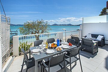 A table and chairs on a balcony overlooking the ocean
