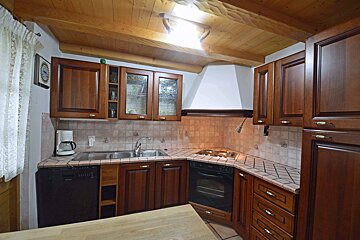A kitchen with wooden cabinets and a black dishwasher
