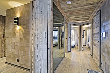 A hallway with wood paneling and mirrors leading to a bedroom