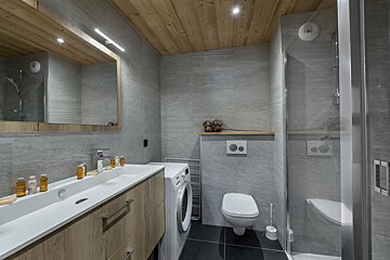 A bathroom with a toilet a sink and a washing machine