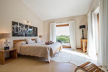 A bedroom with a large bed and a painting on the wall