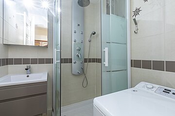A bathroom with a washing machine and a shower