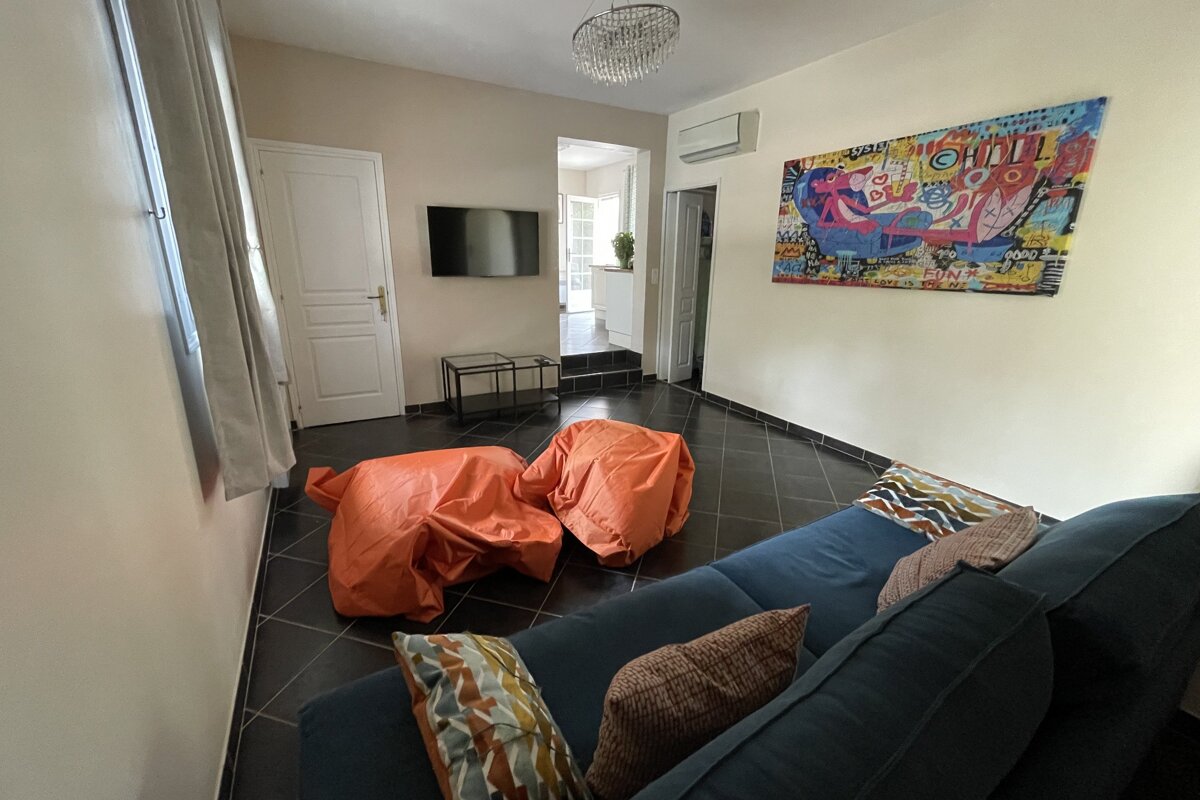 A living room with a blue couch and orange bean bag chairs