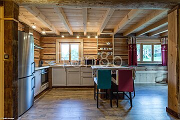 A kitchen in a log cabin with a stainless steel refrigerator