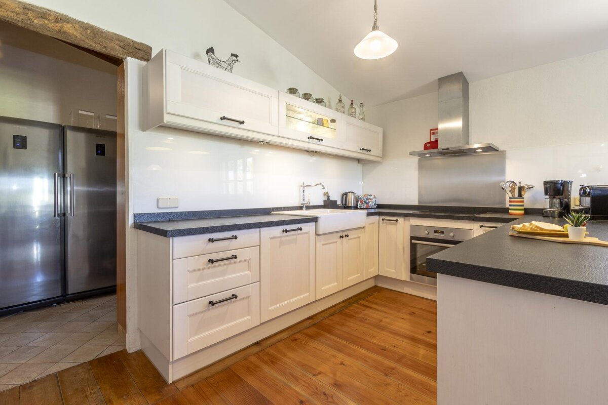 A kitchen with white cabinets and a stainless steel refrigerator