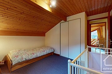 A bedroom with a single bed and a crib with alpine property written on it