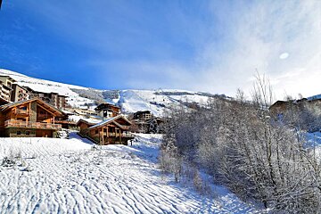 A snowy landscape with a ski resort in the background