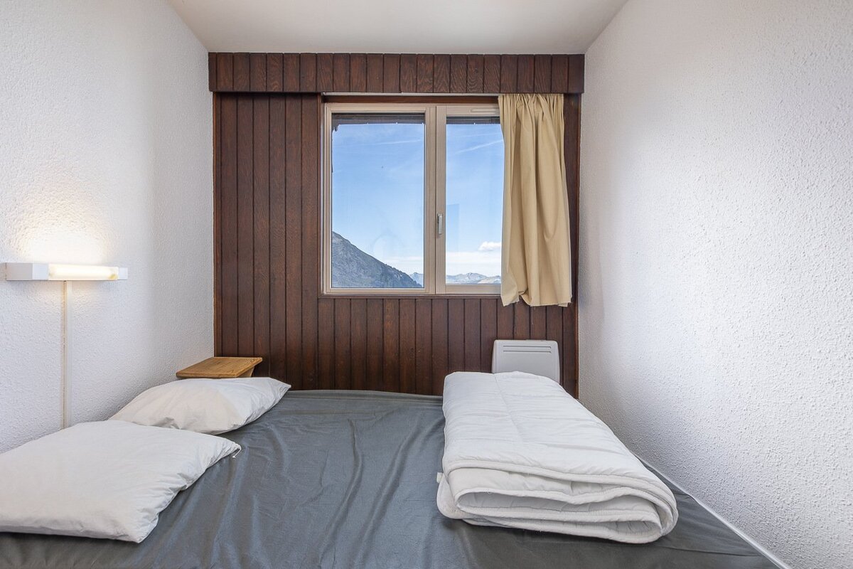 A small bedroom with a bed and a window