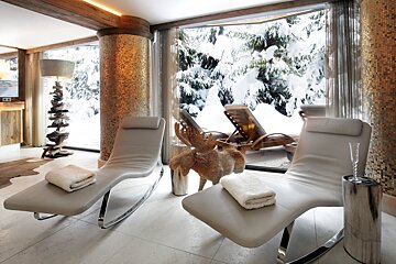 Two lounge chairs in front of a window with snow on the trees