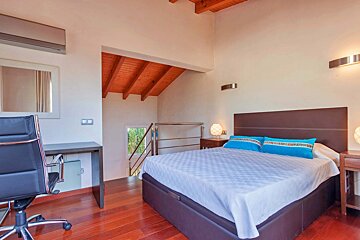 A bedroom with a large bed and a desk