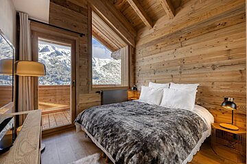 A bedroom with a bed and a window with mountains in the background