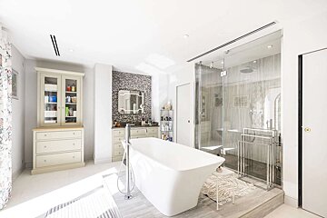 A bright, modern bathroom featuring a freestanding tub, a large glass shower, and elegant cabinetry, all illuminated by natural light.