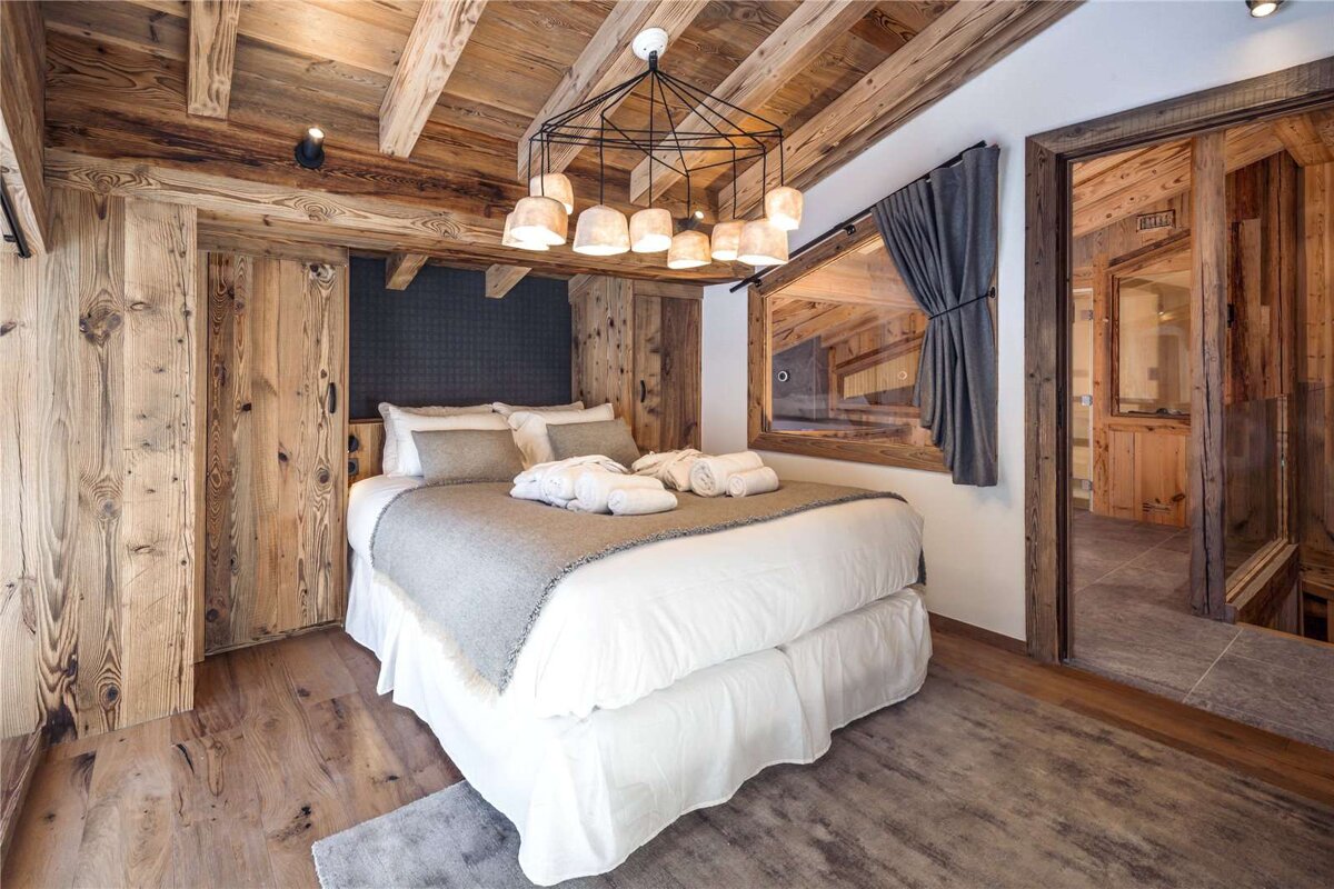 A bedroom with wooden walls and a bed with white sheets