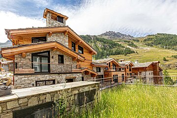 A large stone building with a balcony and mountains in the background