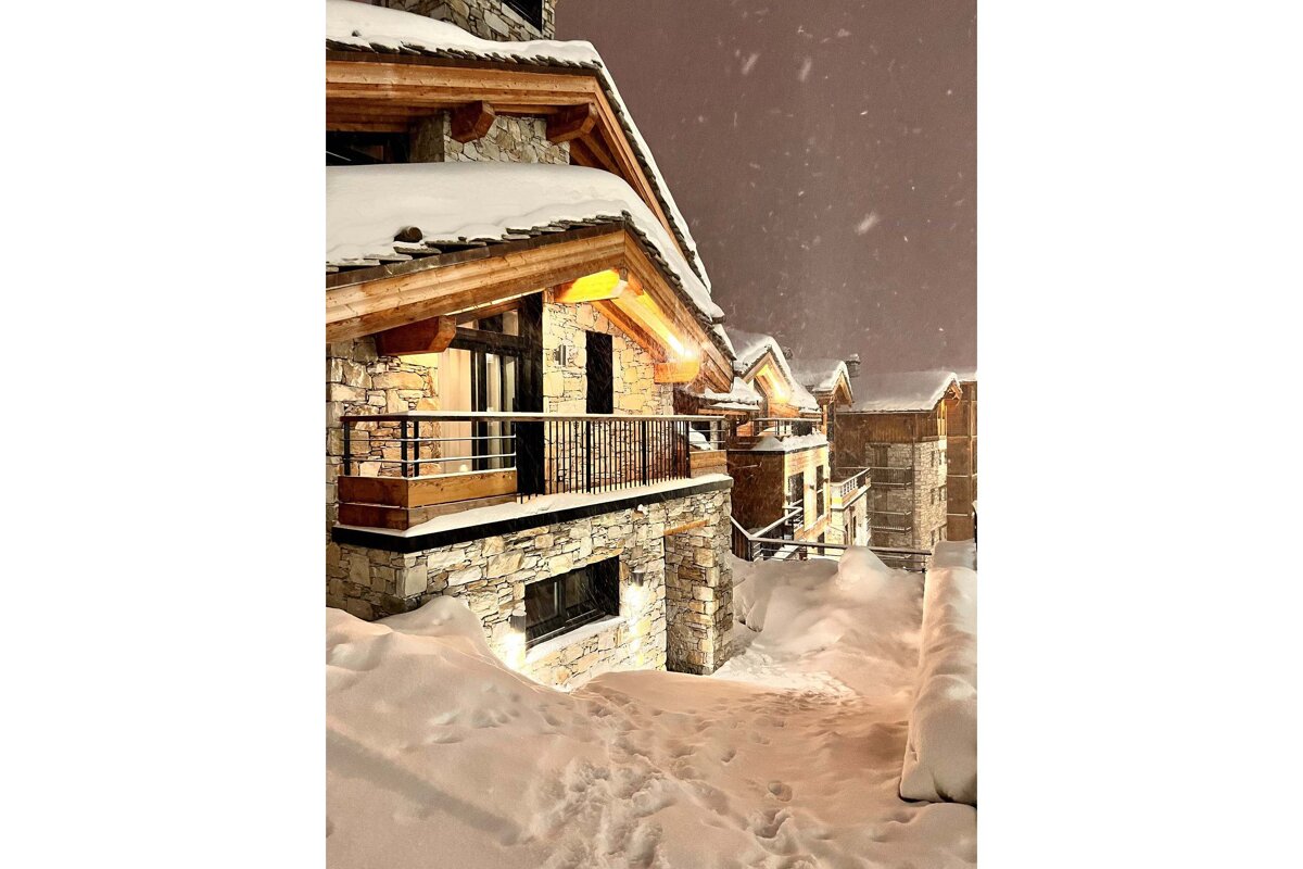 A large stone building with a balcony and mountains in the background