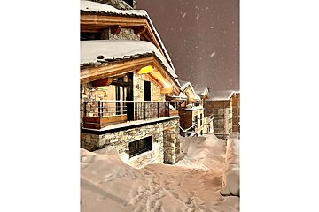 A large stone building with a balcony and mountains in the background