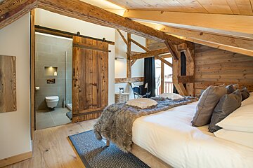 A bedroom with a sliding barn door leading to a bathroom