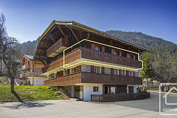 A large wooden building with a yellow arrow pointing to the balcony