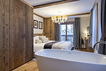 A bedroom with a large bed and a bathtub