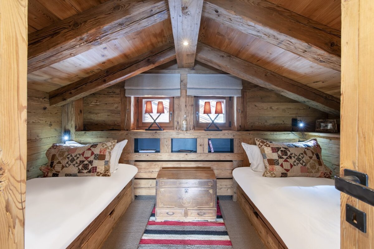 A bedroom with two beds and a trunk on the floor