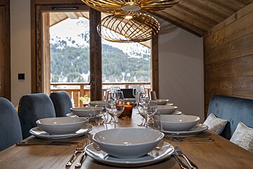 A dining room table set with bowls plates glasses and silverware