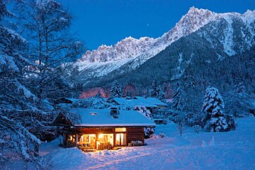 A cabin in the snow with mountains in the background