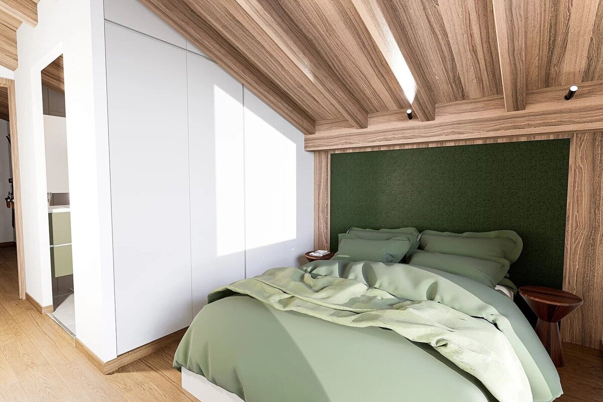 Modern bedroom with a green bed, wooden slanted ceiling, white built-in wardrobe, and an open bathroom view.
