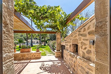 A stone wall with a wooden pergola over it
