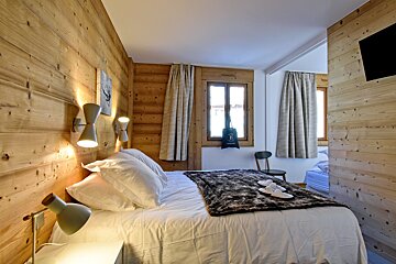 A bedroom with a bed and a bag with the letter b on it