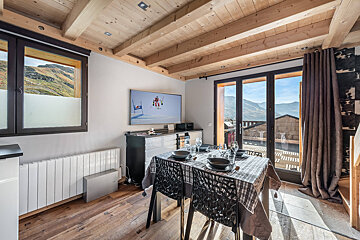 A dining room with a table and chairs and a flat screen tv