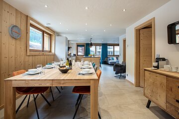 A dining room with a wooden table and orange chairs