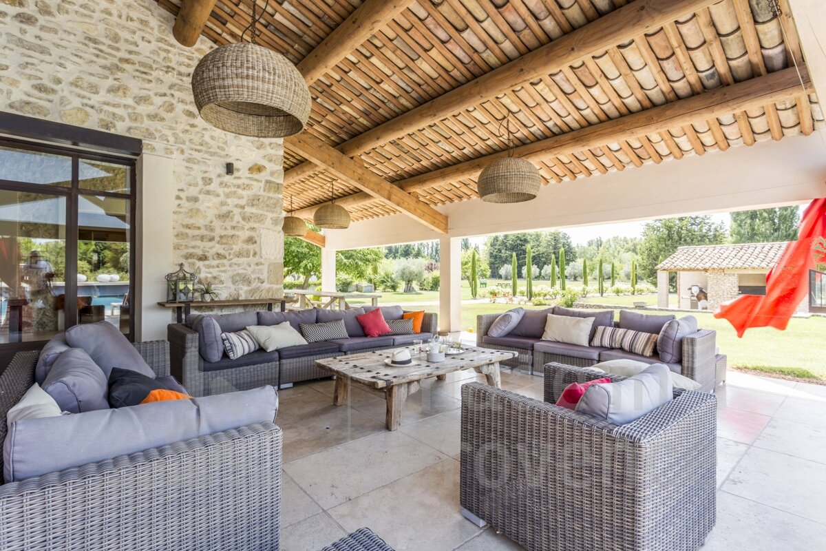 A patio with wicker furniture under a wooden roof