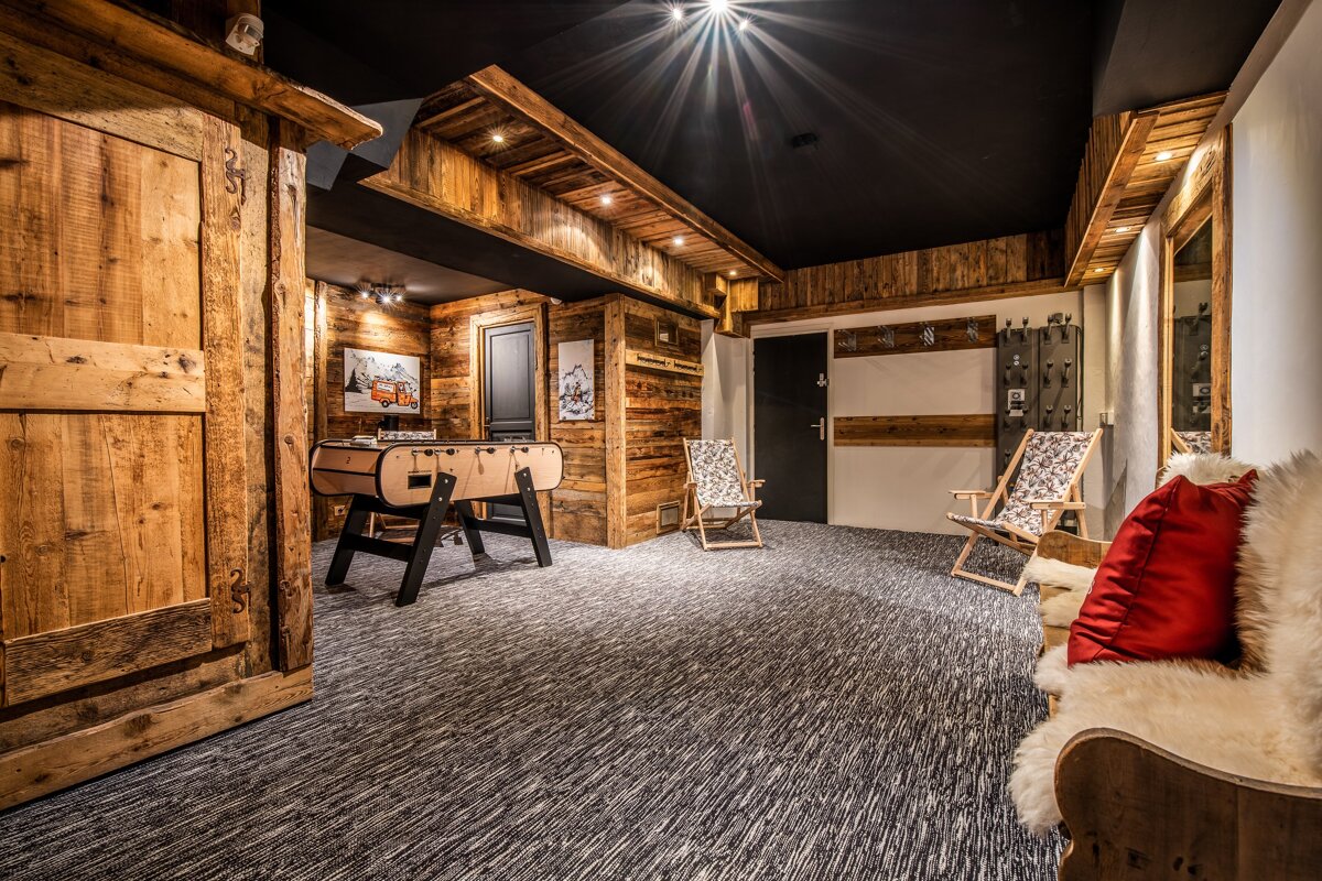 Rustic chalet game room featuring wood paneling, a foosball table, lounge chairs, and cozy fur-covered seating.