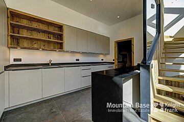 A kitchen with a staircase and the words mountain base knight immobilier real estate on the bottom