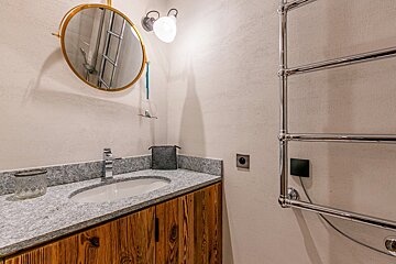 A bathroom with a sink and a round mirror