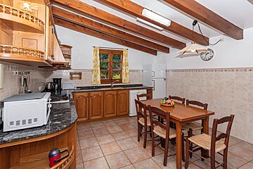 A kitchen with a table and chairs and a clock on the wall
