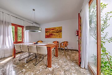 A dining room with a table and chairs and a painting on the wall