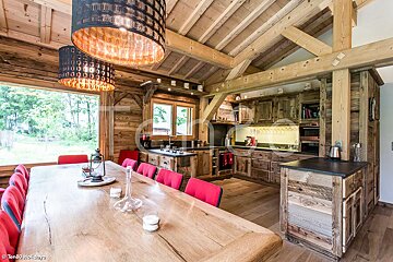 A kitchen with a large wooden table and red chairs