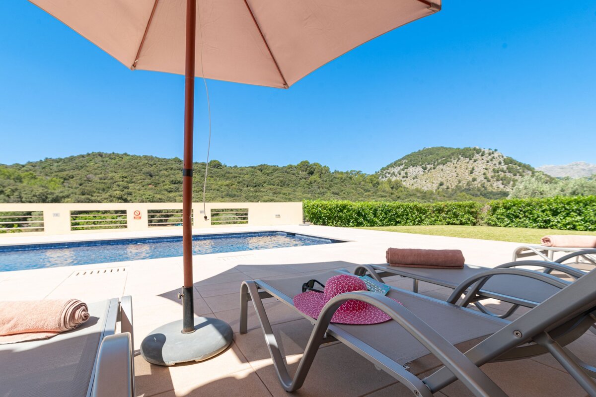 A pink hat sits on a lounge chair under an umbrella