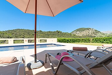 A pink hat sits on a lounge chair under an umbrella
