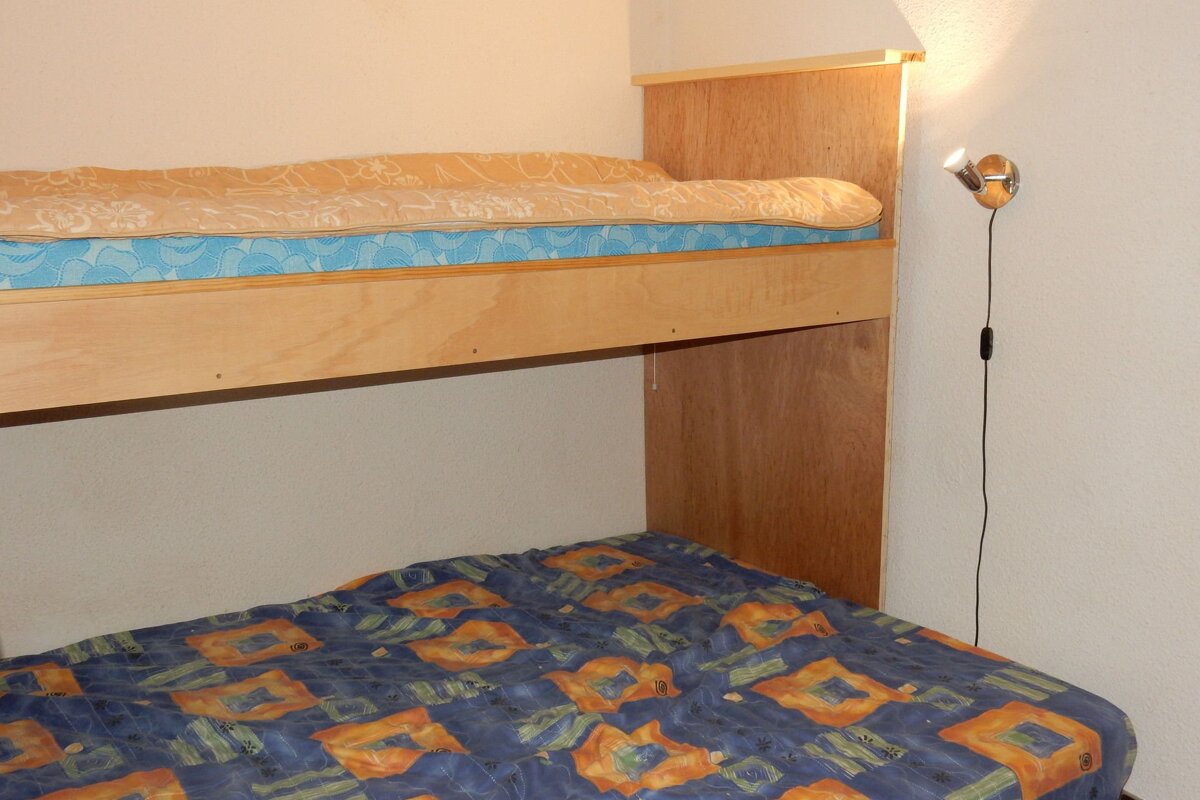 A bunk bed with a blue blanket and a yellow comforter