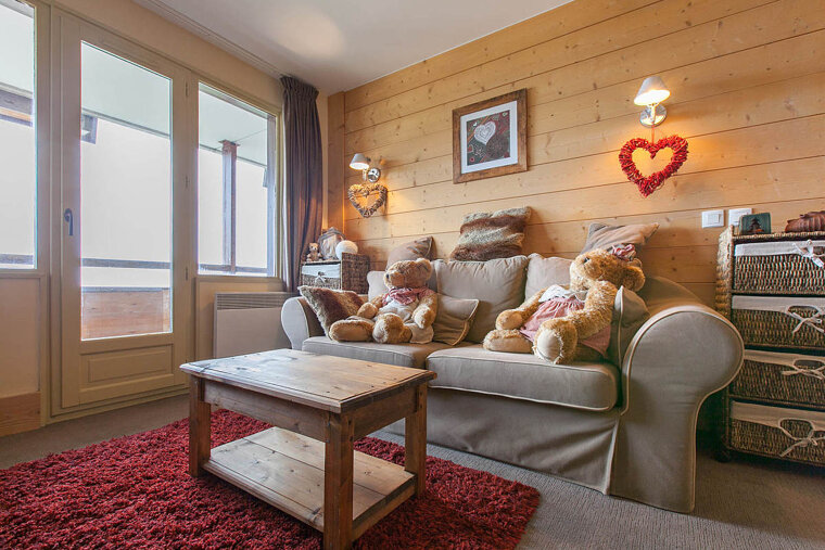 Two teddy bears sit on a couch in a living room
