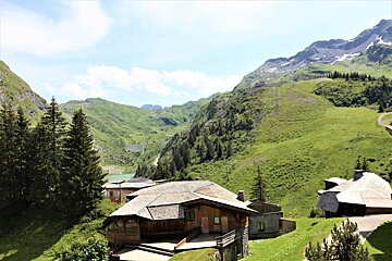 A house in the middle of a valley with mountains in the background